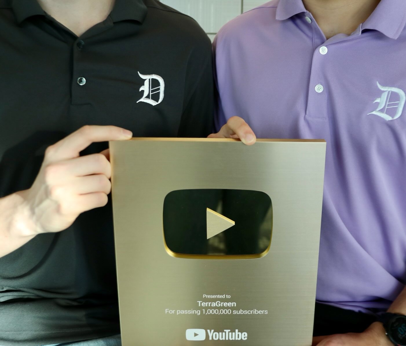 Two people in Donavelli shirts holding TerraGreen’s YouTube Gold Creator Award